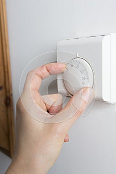 Close Up Of Female Hand On Central Heating Thermostat