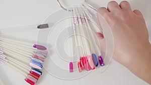 Close-up of female hand choosing the color of nail polish on a palette. Manicure concept