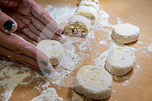 close up of female hand forms a dumpling of cottage cheese dough on a cutting board