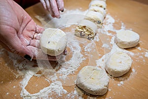 close up of female hand forms a dumpling of cottage cheese dough on a cutting board