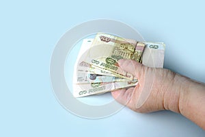 Close-up of a female hand holding a bundle of paper bills of Russian rubles, the concept of receiving a salary, giving a bribe,