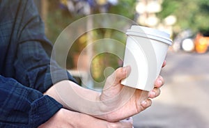 Close-up of female hand holding coffee to take away at early morning