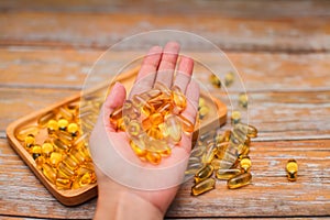 Close up female hand holding gold capsules with food supplement or vitamins