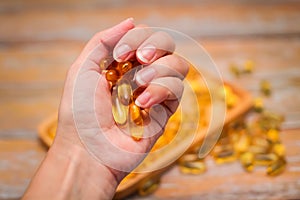 Close up female hand holding gold capsules with food supplement or vitamins