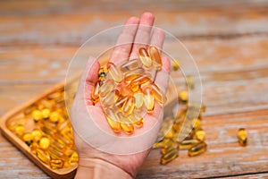 Close up female hand holding gold capsules with food supplement or vitamins