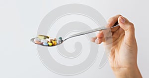Close up of female hand holding spoon with pills