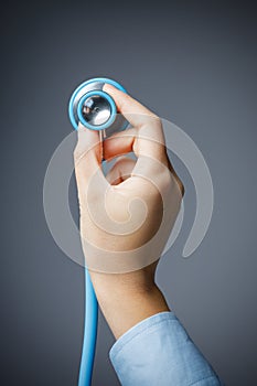 Close up of female hand holding a stethoscope isolated on grey background