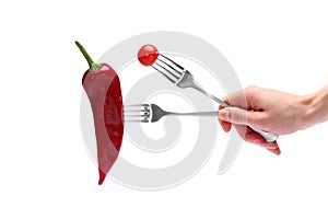 Close up female hand holds fresh red pepper and cherry tomato on forks isolated on white background. Proper nutrition