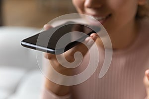 Close up female hand holds smartphone near mouth using speakerphone