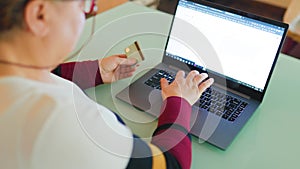 A close-up of a female hand making a purchase through e-commerce on a laptop