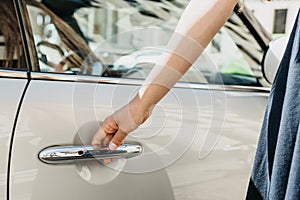 Close-up on a female hand opening the door of a new modern car