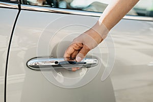 Close-up on a female hand opening the door of a new modern car