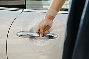 Close-up on a female hand opening the door of a new modern car