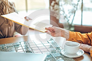 Close up of a female hand passing the papers to the client