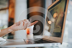 Close up of female hand pointing finger to laptop screen