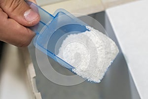 Close up female hand pour the washing powder detergent into machine d