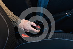 Close-up of female hand pressing button to remove seat belt inside her car.