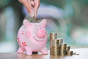 Close up female hand putting coin into piggy bank, save money for future