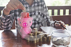 Close up female hand putting coin into piggy bank, save money for future