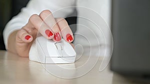 Close up. female hand with red manicure uses a computer mouse