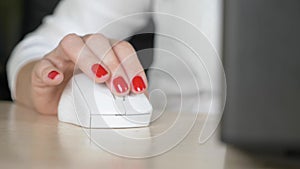 Close up. female hand with red manicure uses a computer mouse