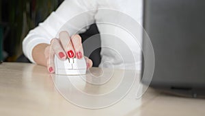 Close up. female hand with red manicure uses a computer mouse