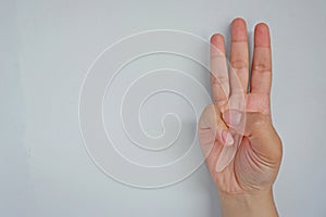 Close-up of female hand showing three fingers  on grey background. Side view close up details.