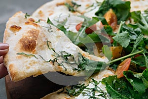 Close up Female hand take a piece of Fresh italian pizza with tomatoes, cheese, basil on black stone table. Copy space