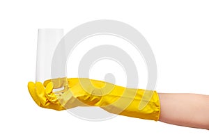 Close up of female hand in yellow protective rubber glove holding clean transparent drinking glass