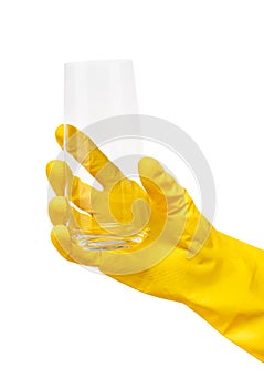 Close up of female hand in yellow protective rubber glove holding clean transparent drinking glass