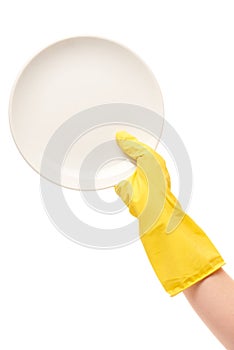 Close up of female hand in yellow protective rubber glove holding clean white plate against white