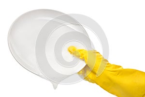 Close up of female hand in yellow protective rubber glove holding clean white plate in foam