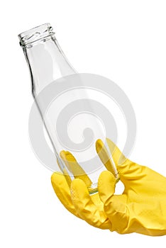 Close up of female hand in yellow protective rubber glove holding empty clean transparent glass milk bottle