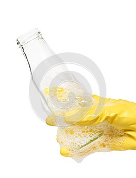 Close up of female hand in yellow protective rubber glove holding empty clean transparent glass milk bottle in foam