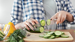 Close-up female hands chopping fresh organic cucumber using knife cooking healthy food salad