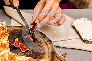 Close up female hands cutting fig with knife