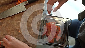 Close up of female hands discarding carrot offcuts into bin. High quality