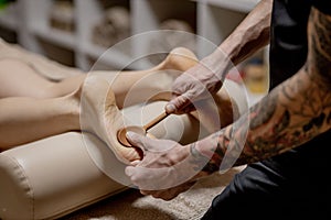 Close-up of female hands doing foot massage. Woman enjoyingreflexology foot massage in wellness spa
