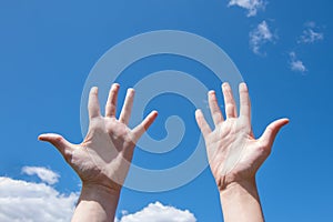 Close-up of female hands, empty open palms on a background of blue sky. Number ten in sign language. Copy space