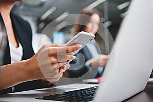 Close-up of female hands hold modern smartphone at her workplace at office