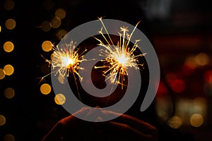 Close up Female hands holding bengal light on black background. Christmas and newyear party sparkle