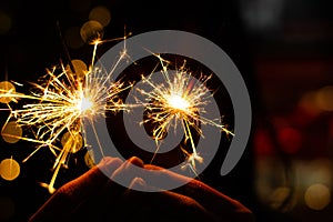 Close up Female hands holding bengal light on black background. Christmas and newyear party sparkle