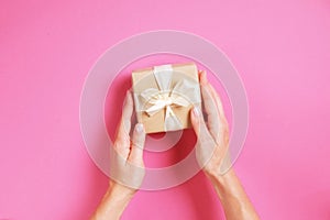 Close up of female hands holding birthday gift in vintage craft paper wrapping. Femenine composition with present in woman`s arms