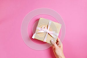 Close up of female hands holding birthday gift in vintage craft paper wrapping. Femenine composition with present in woman`s arms
