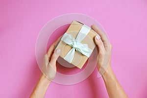 Close up of female hands holding birthday gift in vintage craft paper wrapping. Femenine composition with present in woman`s arms