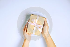 Close up of female hands holding birthday gift in vintage craft paper wrapping. Femenine composition with present in woman`s arms