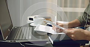 Close up of female hands holding a contract or financial report and taking notes at the workplace.