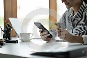 Close up female hands holding credit card and smartphone, young woman paying online, using banking service, entering