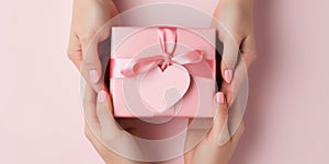 Close up on female hands holding a gift in a pink heart presents for valentine day, birthday, mother\'s day
