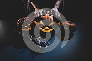 Close-up of female hands holding a halloween pumpkin in the dark